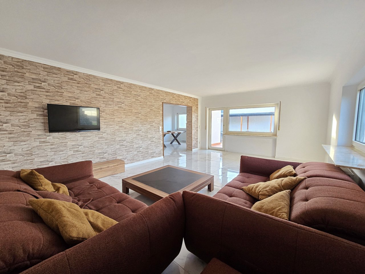 Wohnzimmer mit Zugang zur Terrasse und Blick ins Esszimmer